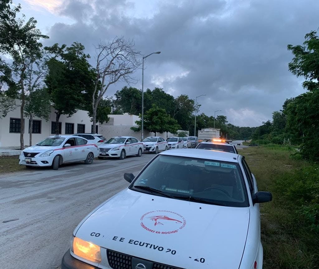 Taxi drivers waiting beside their vehicles at a taxi stand in Tulum, Quintana Roo