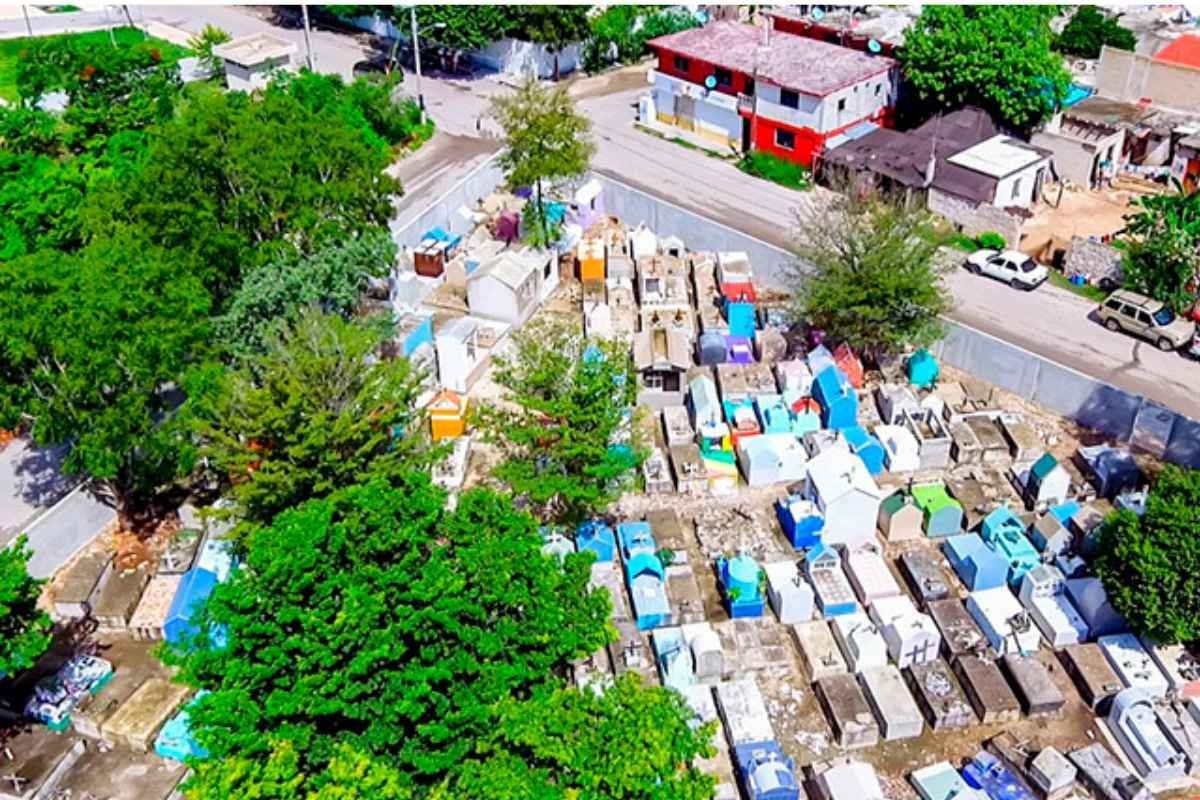 Aerial view of a cemetery with colorful tombs, surrounded by trees and nearby houses and streets