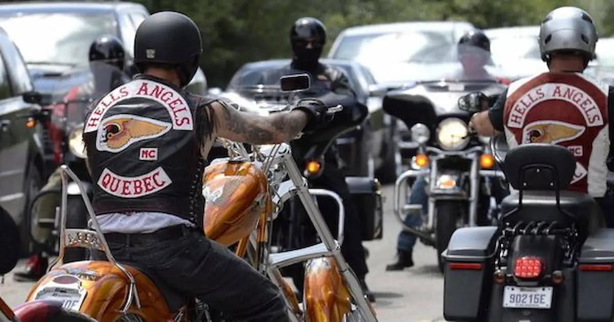 A group of bikers wearing Hells Angels vests ride on motorcycles along a road surrounded by cars. The scene captures the essence of motorcycle culture and camaraderie.$# CAPTION