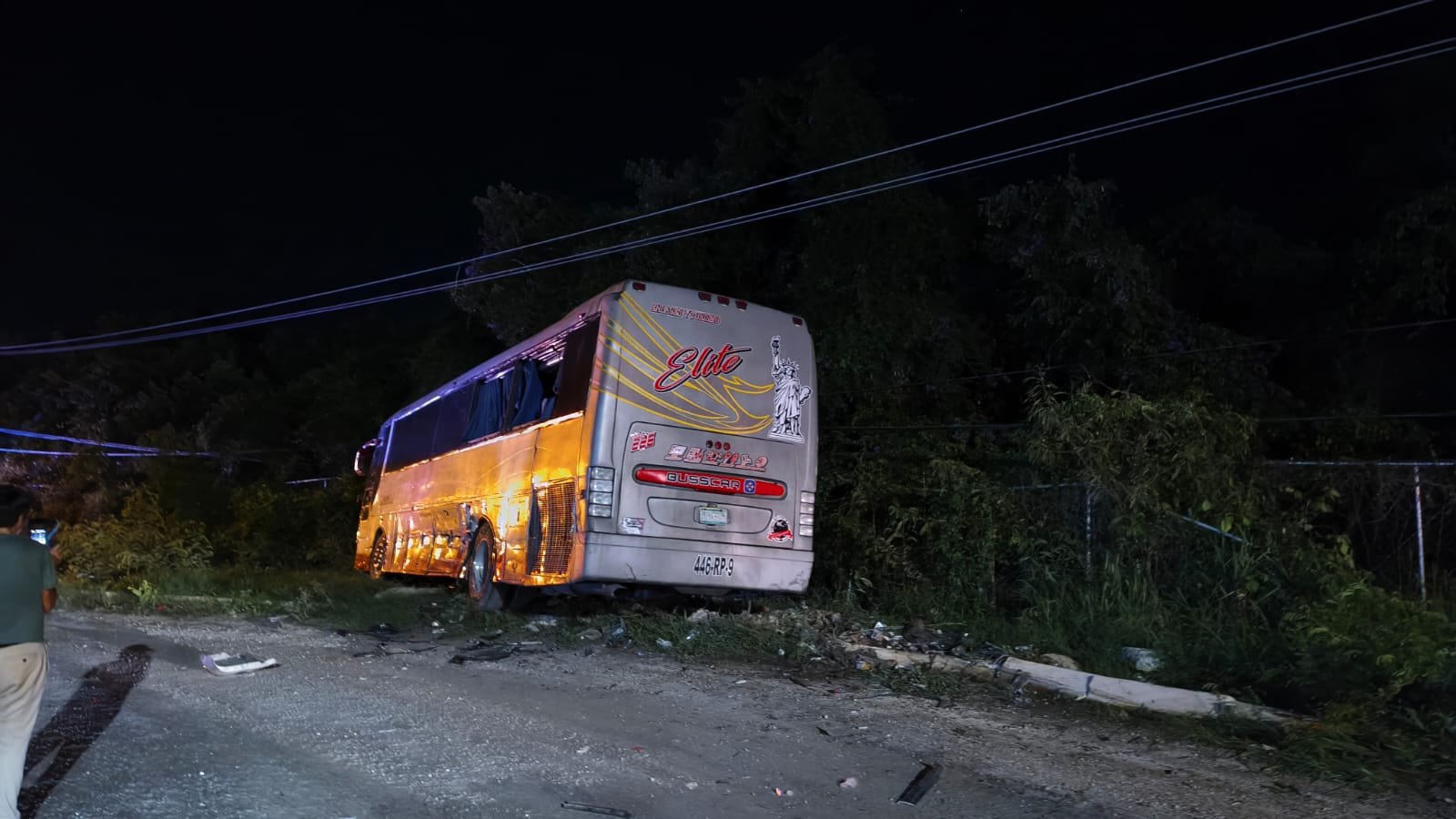 Damaged bus resting against the perimeter wall of the Mayakoba complex after a collision with a trailer on the federal highway near Playa del Carmen