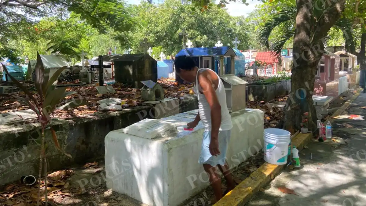 A worker cleans and paints a grave at the Los Olivos cemetery in Cancún, where funeral and burial costs can exceed 100,000 pesos