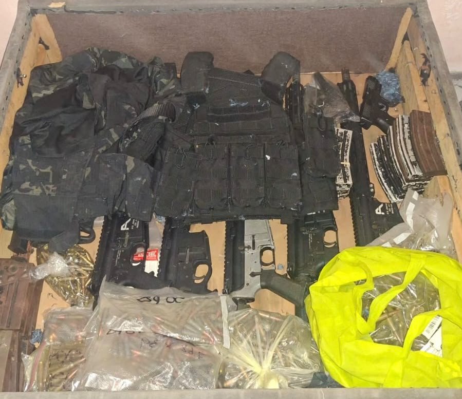 Security personnel stand outside a home in Cancún's Región 225 after a raid in which investigators seized rifles, handguns and ammunition