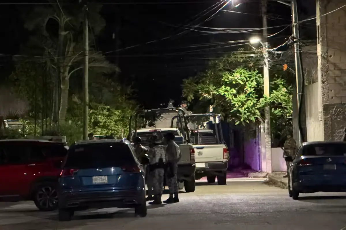 Police officers stand outside a sealed property in Cancún following three simultaneous raids targeting human trafficking and drug sales