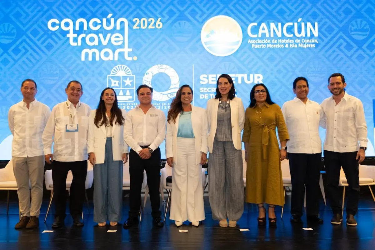 A group of professionals at the Cancun Travel Mart 2026 event posing for a photo on stage.$# CAPTION