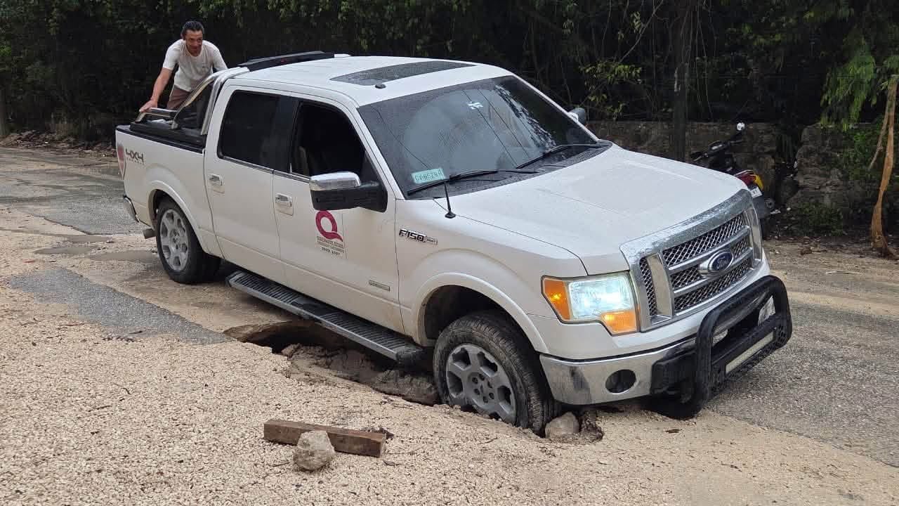 Several vehicles stuck in water-filled trenches left by roadwork on Avenida Colegios in Cancún after heavy rain