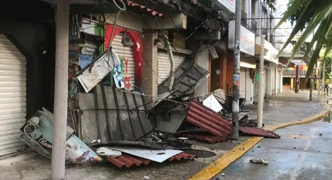 Crumbled concrete and debris from the abandoned Hotel Agua Azul scattered across the sidewalk on Avenida 10 in Playa del Carmen