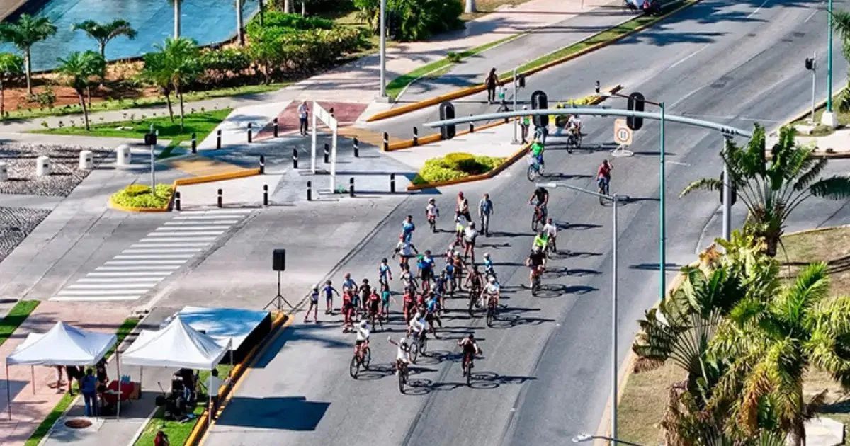 Families riding bicycles along a wide avenue in Cancun during an evening recreational cycling event