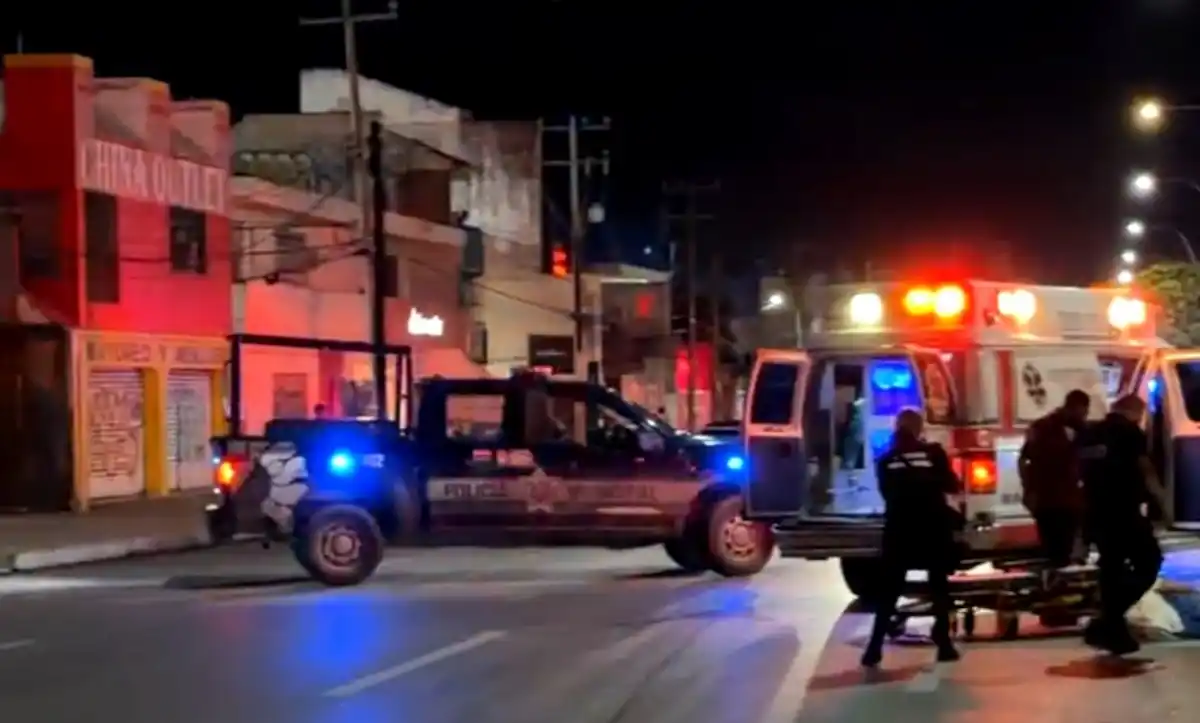 A police vehicle and an ambulance are responding to an incident at night, with emergency lights flashing in a dimly lit street.$# CAPTION