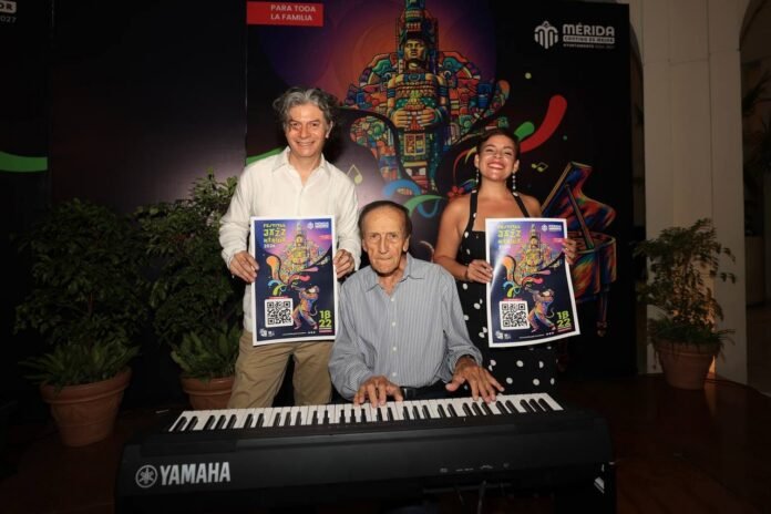 Three individuals pose together in front of a colorful backdrop, with one playing a keyboard and holding a festival poster - 14102026