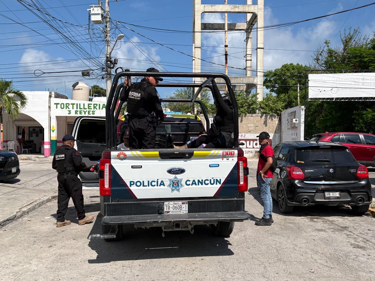 Police vehicles and officers outside a home near El Parián market in Cancún, Quintana Roo, where four Cuban nationals were arrested on counterfeiting charges