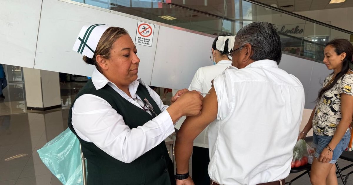 A health worker prepares an influenza vaccine dose at an IMSS vaccination point in Quintana Roo