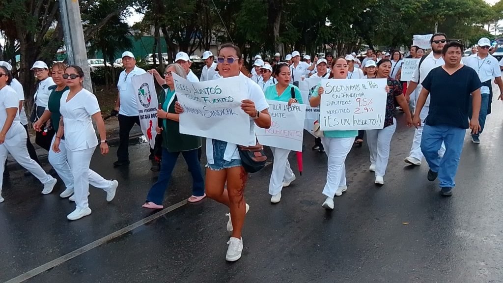 IMSS workers and retirees marching through the streets of Cancún with banners to demand higher wages, medicines and more staff