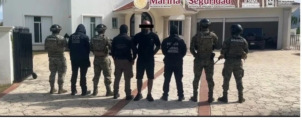 A group of law enforcement officers standing in a line facing away from the camera in front of a residential building.
