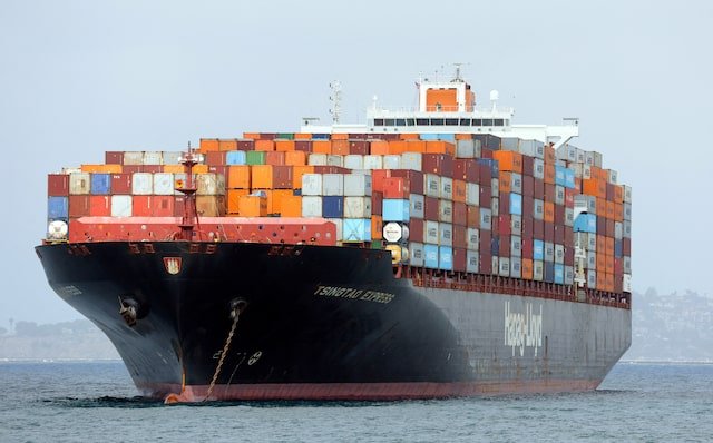 A large cargo ship loaded with colorful containers navigating through the water.$# CAPTION