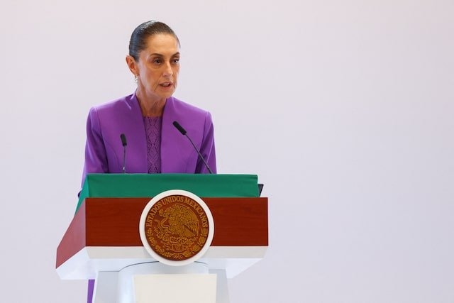 A woman in a purple suit stands at a podium with the emblem of Mexico, speaking at a press conference.$#$ CAPTION