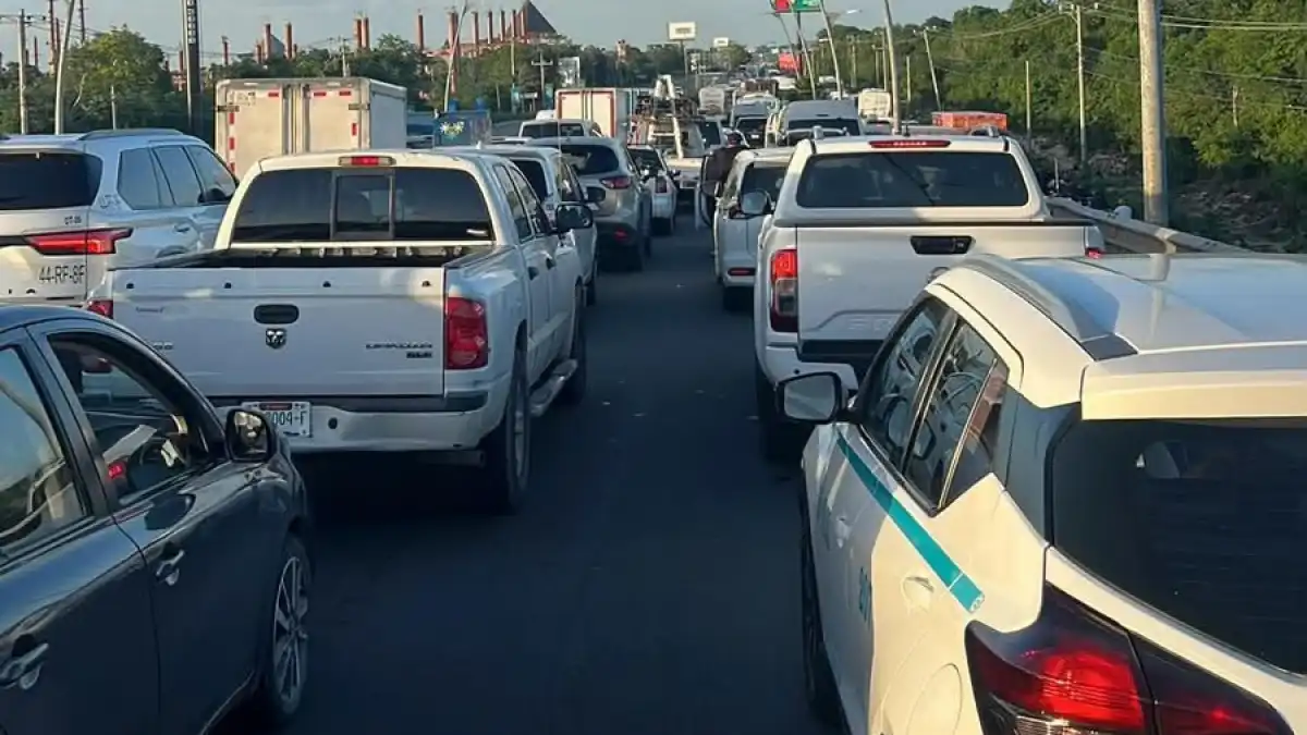 A view from a vehicle of several cars and pickup trucks stopped in heavy traffic on a multi-lane road, with a white sedan in the right foreground and a white pickup truck ahead in the center lane.