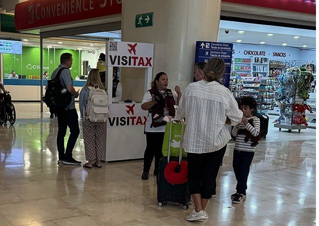 Travelers walking with luggage through a terminal at Cancún International Airport, where tourists have questioned a $30 exit fee charged by airport operator Asur