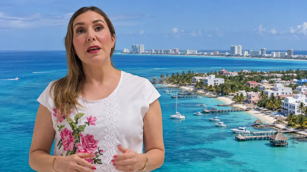 A woman speaks in front of a scenic coastal view with blue waters, boats, and buildings in the background.$# CAPTION