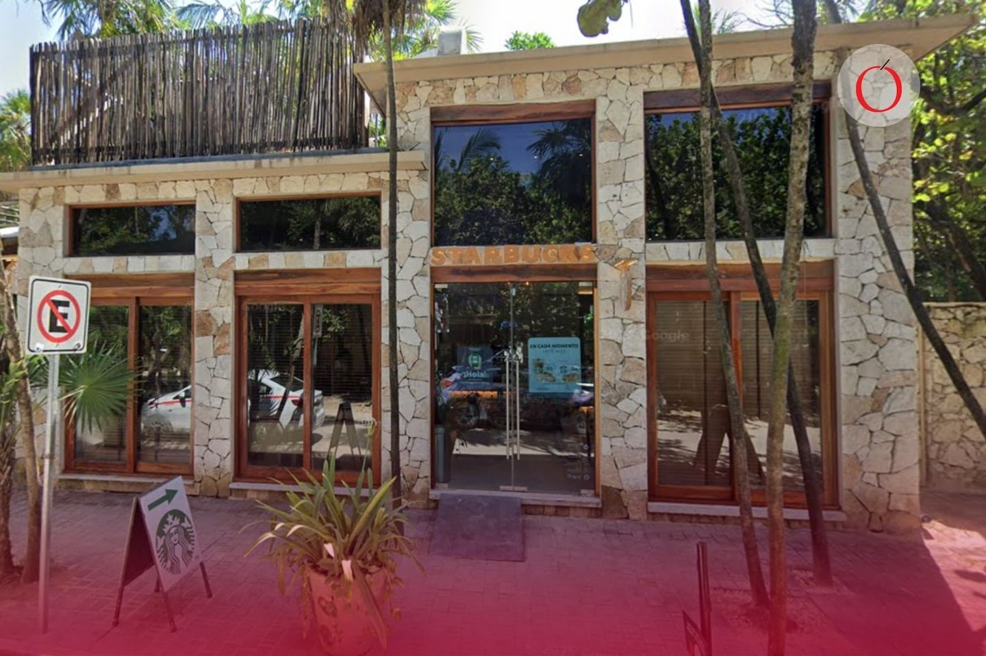 A Starbucks store with a stone exterior and wooden accents surrounded by greenery in a tropical setting.$# CAPTION