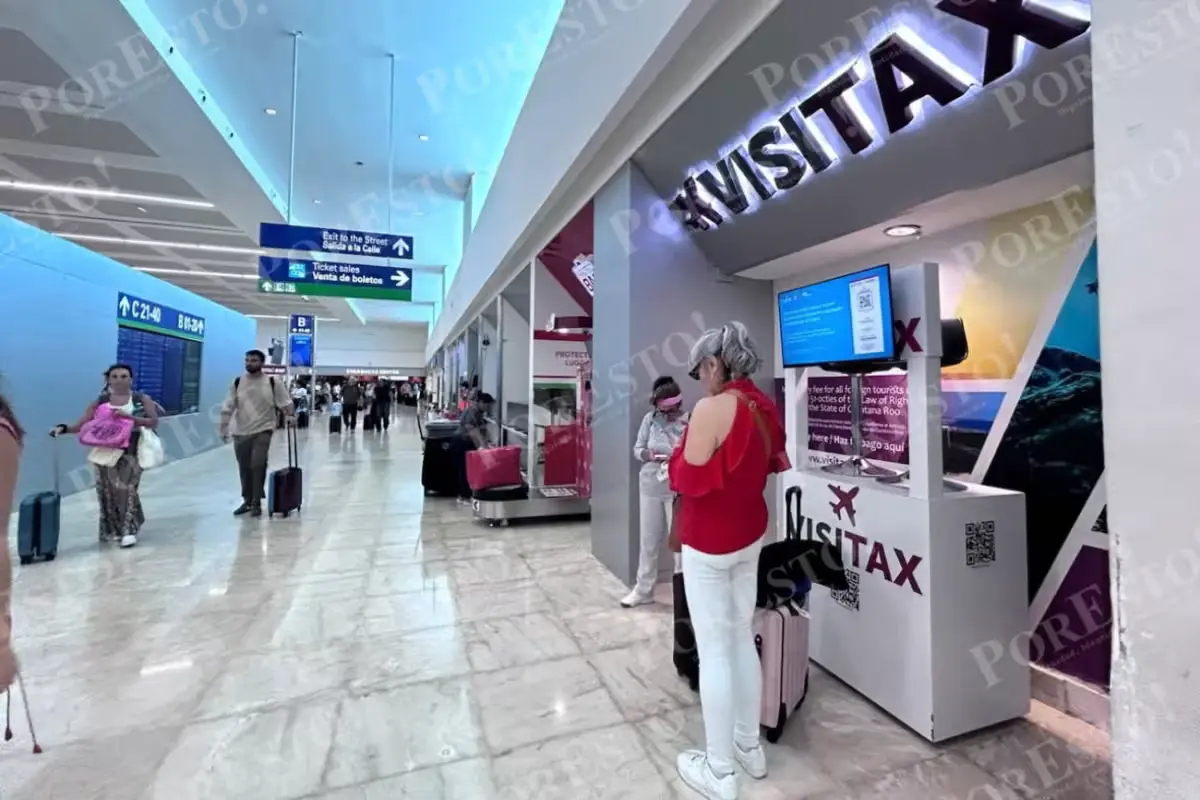 Travelers walk past Visitax payment modules inside Terminal 2 of Cancún International Airport