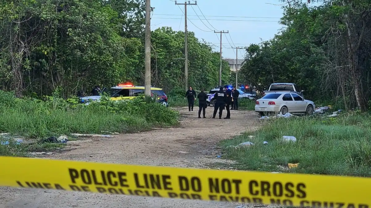 Investigators work near a dirt road bordered by vegetation in Colonia Cuna Maya, Cancún, where the body of a 19-year-old woman was found